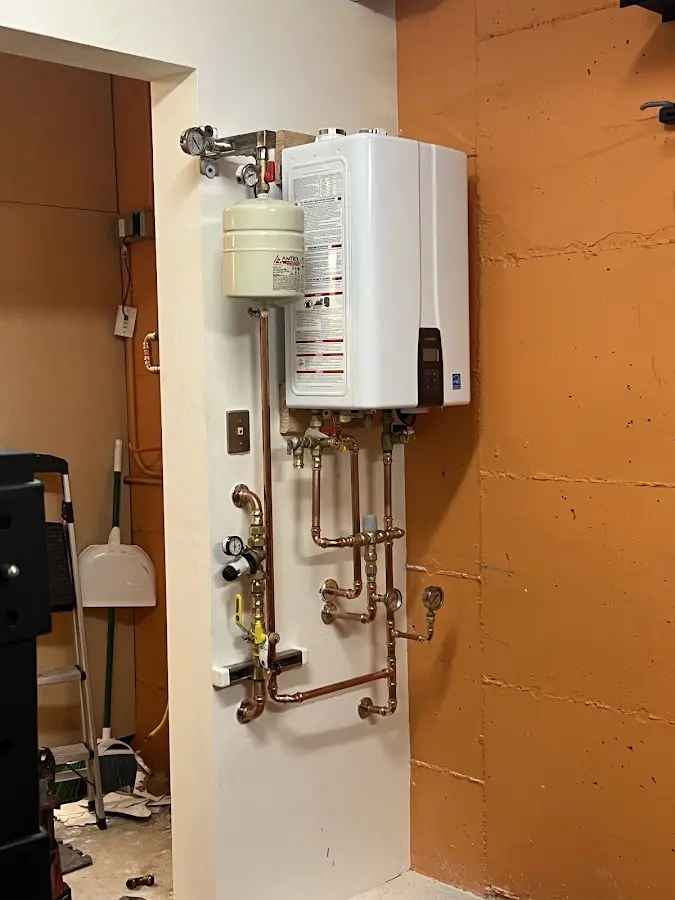 Plumbing technician inspecting water heater connections in Waterford